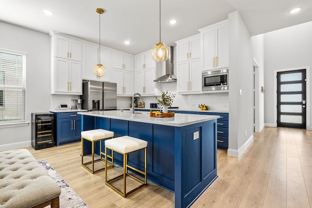 kitchen with light countertops, beverage cooler, blue cabinetry, stainless steel appliances, and a kitchen bar