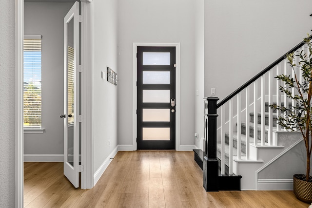 foyer featuring baseboards, wood finished floors, and stairway