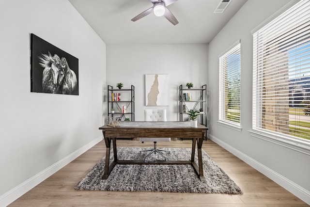 office space featuring visible vents, a ceiling fan, light wood finished floors, and baseboards