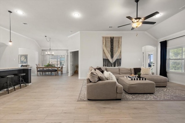 living area with arched walkways, light wood-style floors, ceiling fan with notable chandelier, and crown molding