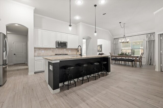 kitchen featuring tasteful backsplash, arched walkways, appliances with stainless steel finishes, and ornamental molding