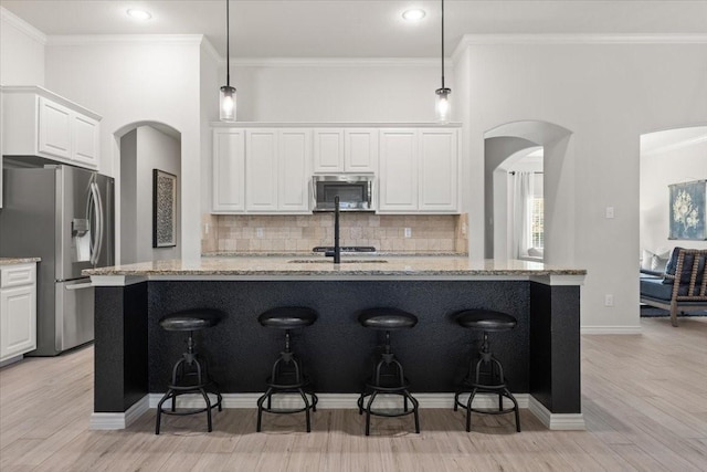 kitchen with light stone countertops, light wood finished floors, white cabinets, and stainless steel appliances