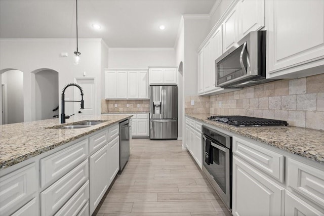 kitchen with tasteful backsplash, white cabinets, a sink, crown molding, and stainless steel appliances
