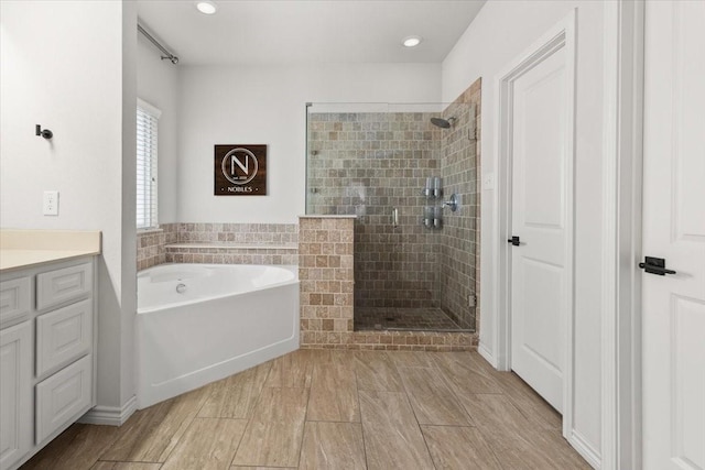 bathroom with a bath, tiled shower, vanity, and recessed lighting