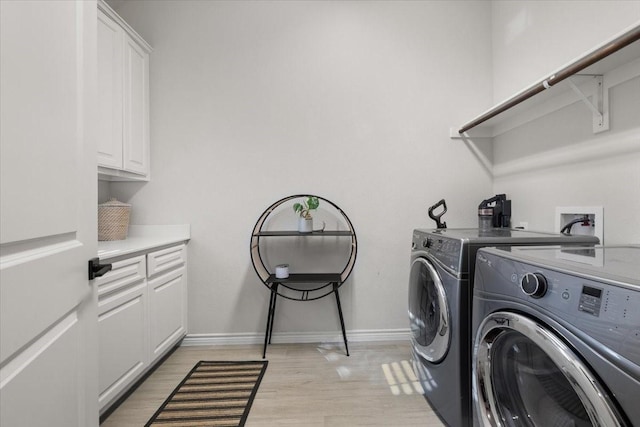 laundry area with light wood finished floors, baseboards, washing machine and clothes dryer, and cabinet space
