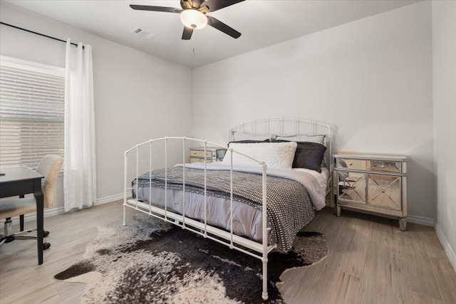 bedroom featuring visible vents, baseboards, ceiling fan, and wood finished floors