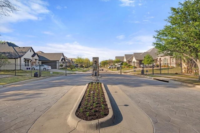 view of road featuring curbs, a residential view, and a gated entry