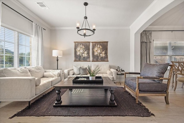 living area featuring an inviting chandelier, ornamental molding, and visible vents