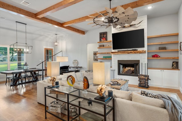 living area with a fireplace, visible vents, ceiling fan with notable chandelier, and wood finished floors