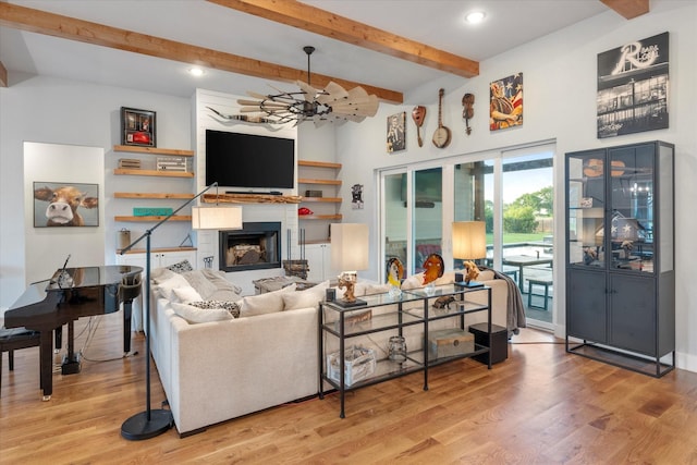 living room featuring wood finished floors, beamed ceiling, and a large fireplace