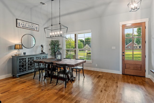 dining space featuring plenty of natural light, visible vents, an inviting chandelier, and wood finished floors