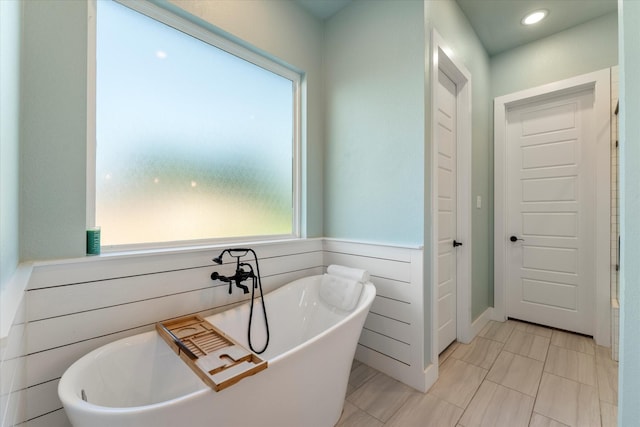 full bath with a soaking tub, wood walls, and a wainscoted wall