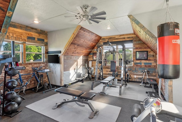 workout room with brick wall, a ceiling fan, a textured ceiling, vaulted ceiling, and wood walls