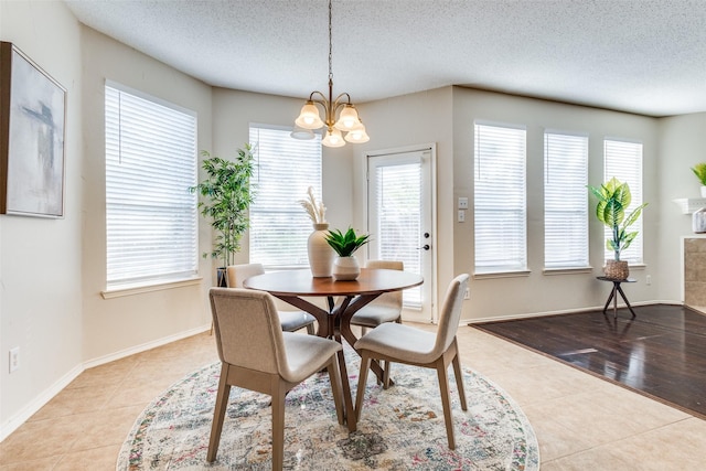 tiled dining area featuring a chandelier, a textured ceiling, and baseboards