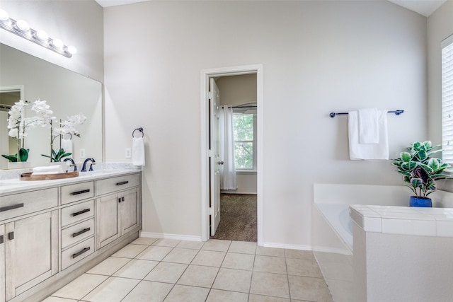 bathroom with a garden tub, a sink, tile patterned floors, double vanity, and baseboards