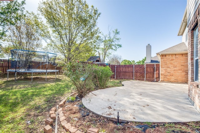 view of yard featuring a patio, a trampoline, and a fenced backyard