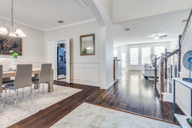 foyer with a decorative wall, arched walkways, visible vents, wood finished floors, and wainscoting