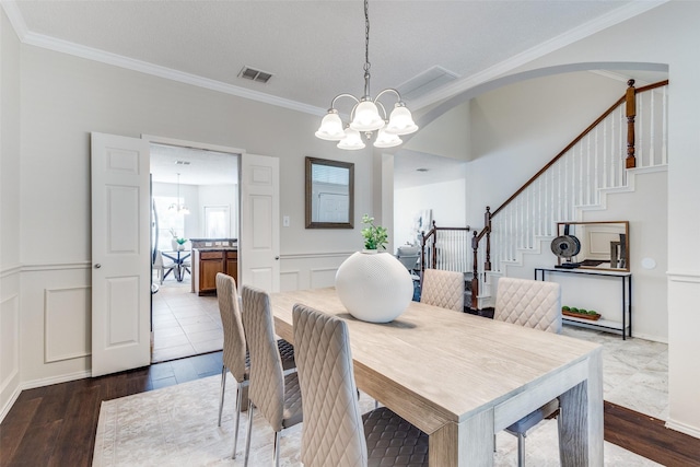 dining area featuring a decorative wall, visible vents, an inviting chandelier, and crown molding