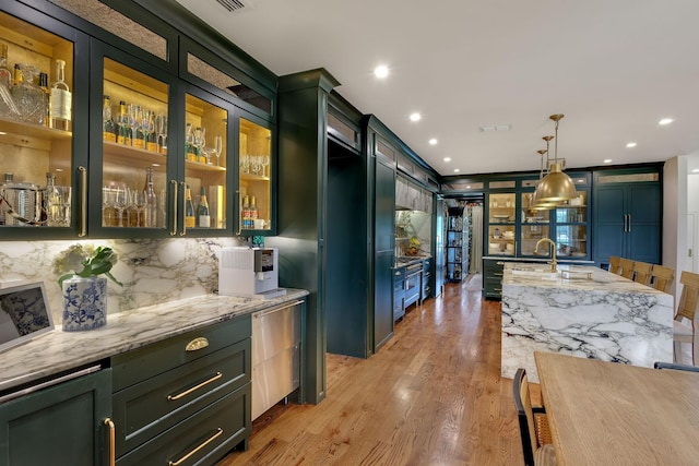 860 Prairie Trl, Argyle, TX 76226 - kitchen with light stone counters, hanging light fixtures, light wood-style floors, backsplash, and green cabinetry