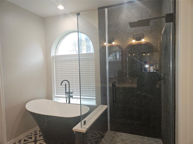 bathroom with a shower stall, a freestanding tub, and baseboards
