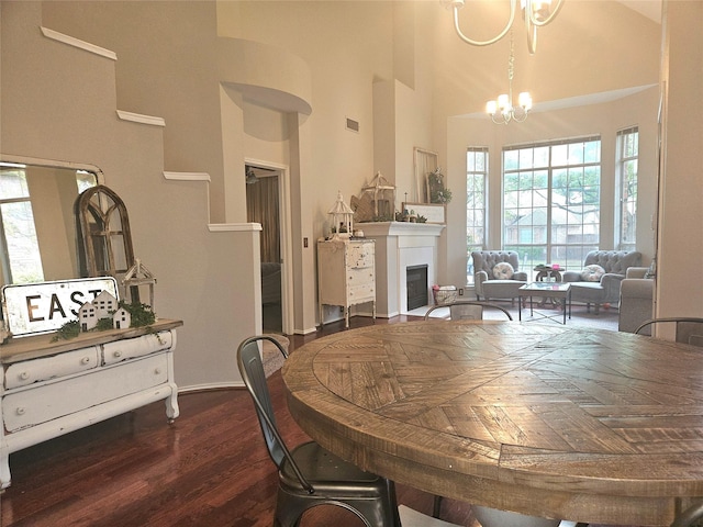dining room with dark wood-style flooring, a notable chandelier, a high ceiling, and a wealth of natural light
