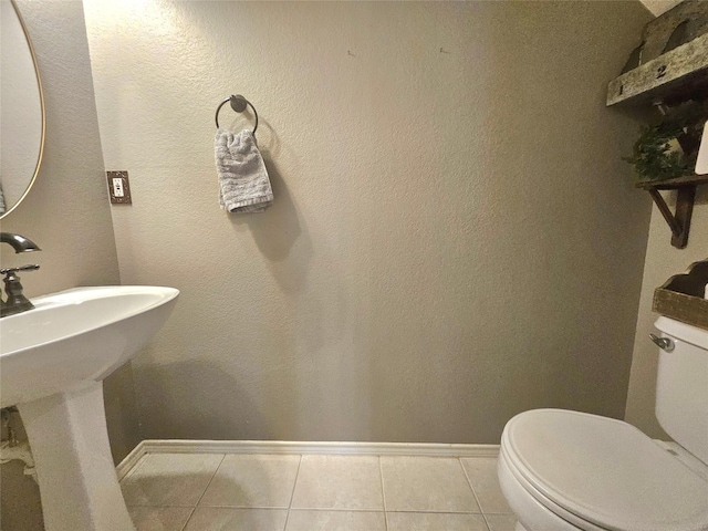 bathroom with tile patterned floors, baseboards, and toilet