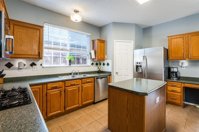kitchen with stainless steel appliances, a sink, dark countertops, and a textured ceiling