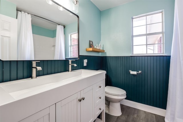 bathroom with wainscoting, toilet, healthy amount of natural light, wood finished floors, and vanity