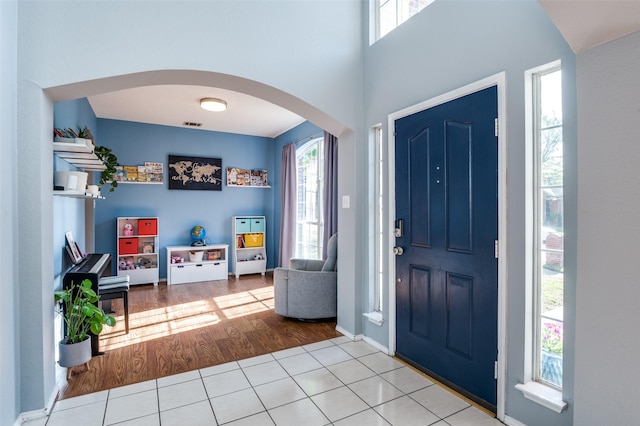 foyer featuring arched walkways, wood finished floors, and baseboards