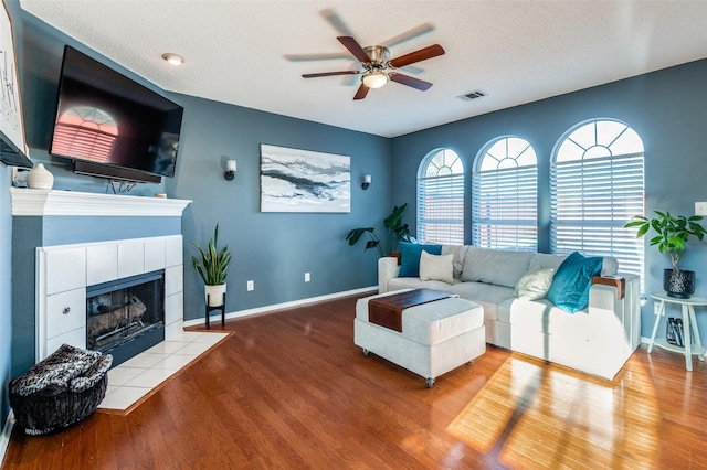 living room featuring ceiling fan, wood finished floors, baseboards, and a fireplace