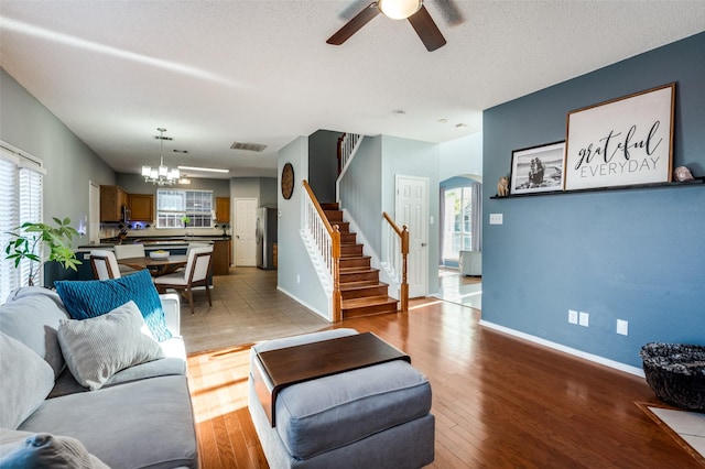 living room with stairway, ceiling fan, arched walkways, a chandelier, and healthy amount of natural light