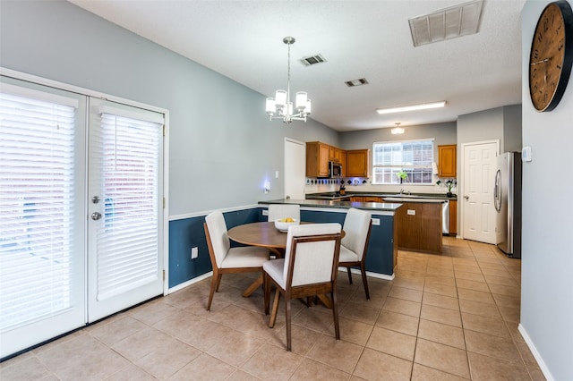 dining space with a chandelier, light tile patterned floors, and baseboards