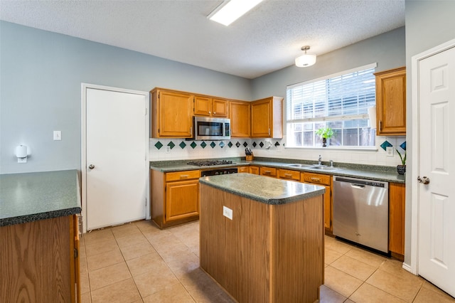 kitchen with appliances with stainless steel finishes, a sink, dark countertops, tasteful backsplash, and a textured ceiling