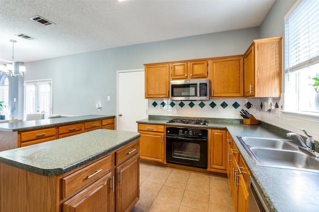 kitchen featuring black oven, a sink, stainless steel microwave, gas cooktop, and dark countertops