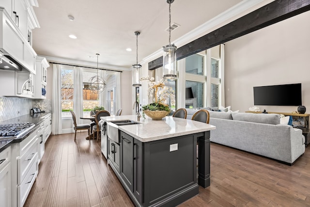 kitchen with a chandelier, white cabinetry, a center island with sink, dark wood-type flooring, and extractor fan