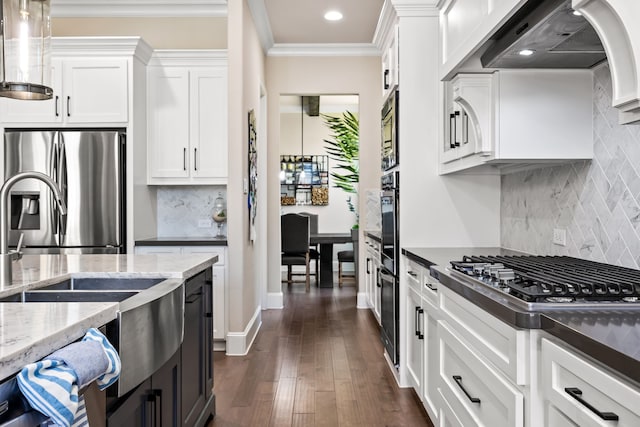kitchen featuring wall chimney exhaust hood, ornamental molding, dark wood finished floors, white cabinetry, and stainless steel appliances