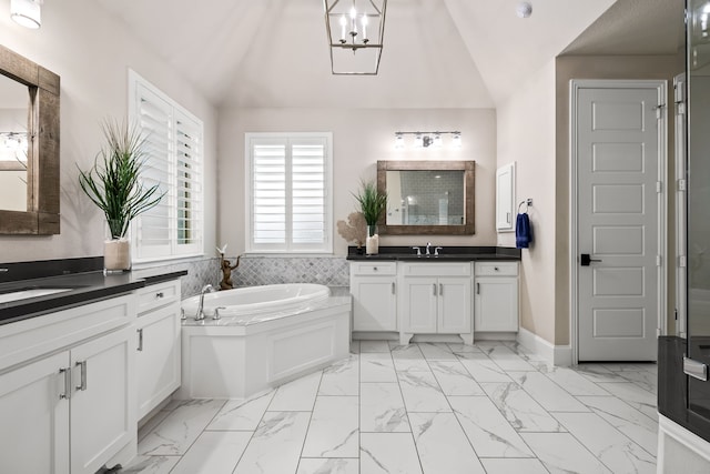 full bathroom with a bath, marble finish floor, a sink, and lofted ceiling