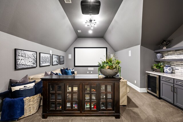 home theater featuring baseboards, vaulted ceiling, visible vents, beverage cooler, and light colored carpet