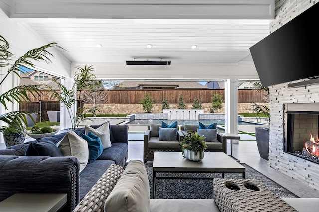 view of patio / terrace with a fenced backyard and an outdoor living space with a fireplace