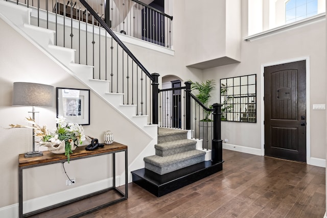 entryway with hardwood / wood-style floors, a towering ceiling, baseboards, and stairway
