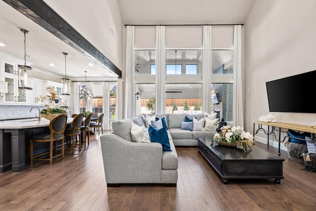 living area with a high ceiling, baseboards, and dark wood-style floors