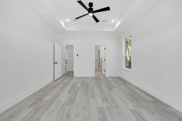 unfurnished bedroom with visible vents, baseboards, light wood-style floors, a tray ceiling, and recessed lighting