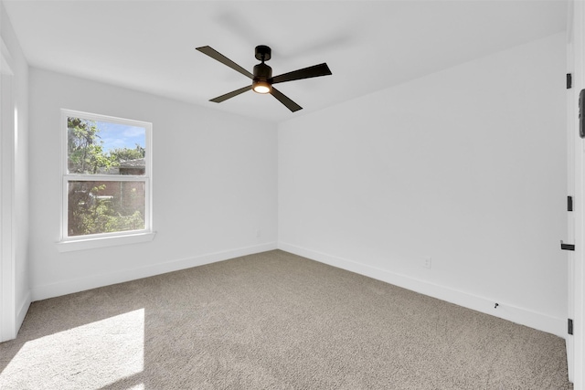 carpeted spare room with baseboards and a ceiling fan
