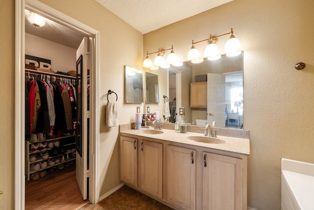 1435 Greenbrook Dr, Rockwall, TX 75032 - bathroom with a textured ceiling, double vanity, a sink, and a spacious closet