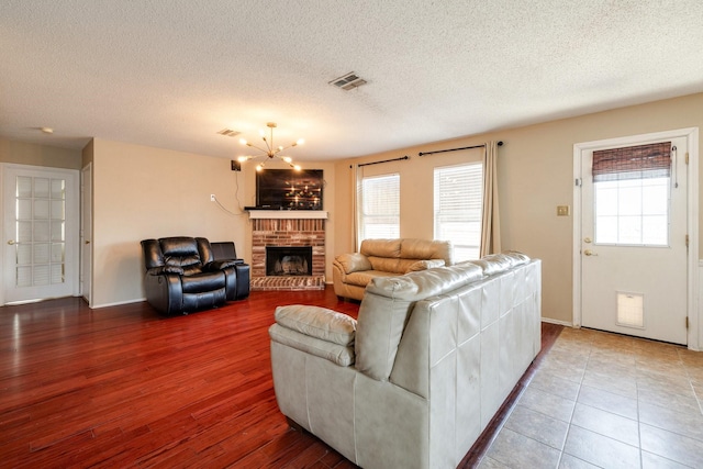 1435 Greenbrook Dr, Rockwall, TX 75032 - living area with an inviting chandelier, a textured ceiling, visible vents, a brick fireplace, and baseboards