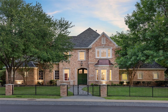 view of front of house with a front yard, roof with shingles, brick siding, and a fenced front yard