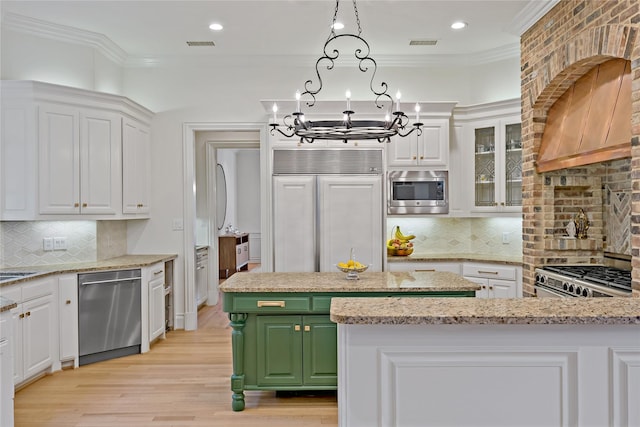 kitchen featuring crown molding, a notable chandelier, built in appliances, and white cabinets