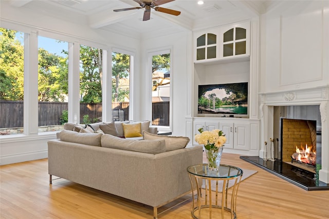 living area featuring light wood-style floors, beamed ceiling, a ceiling fan, coffered ceiling, and a high end fireplace