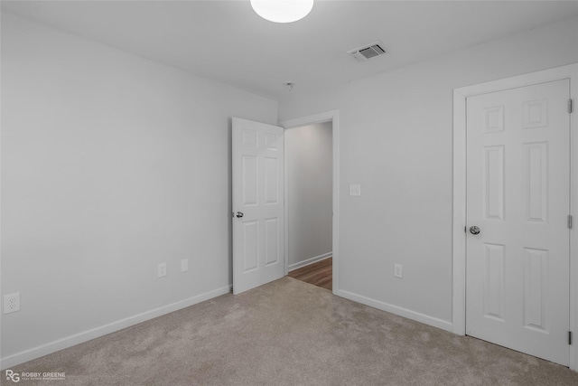unfurnished bedroom with carpet flooring, baseboards, and visible vents