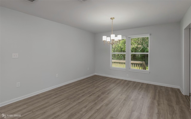 unfurnished room featuring baseboards, a chandelier, and wood finished floors